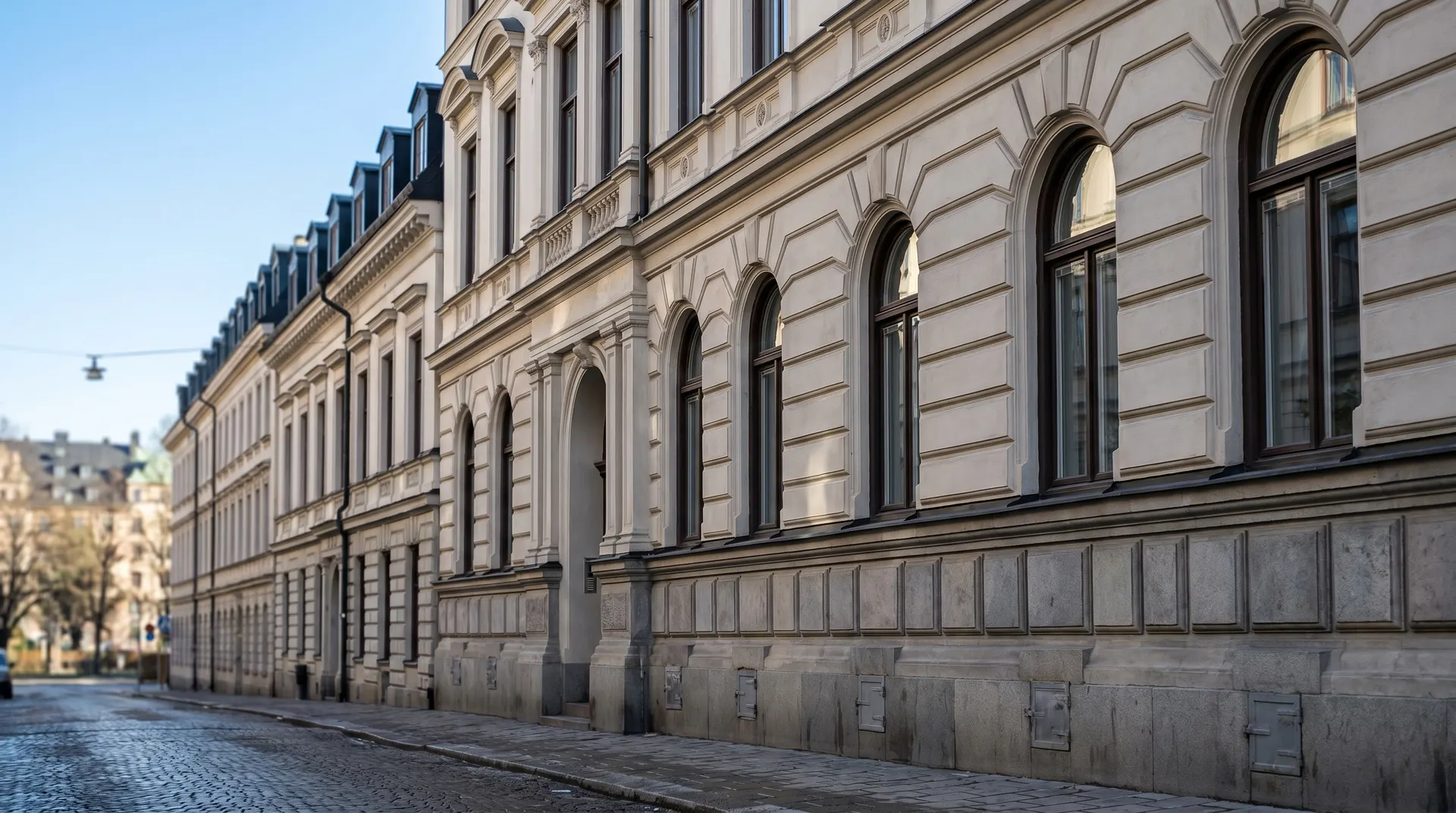Klassisk fasad med arkadgångar längs en kullerstensgata i Europa.