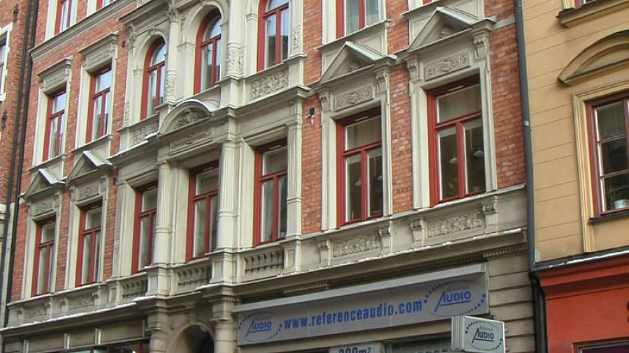 Klassisk vit stenbyggnad integrerad med modern glasarkitektur och gråa betongbyggnader.