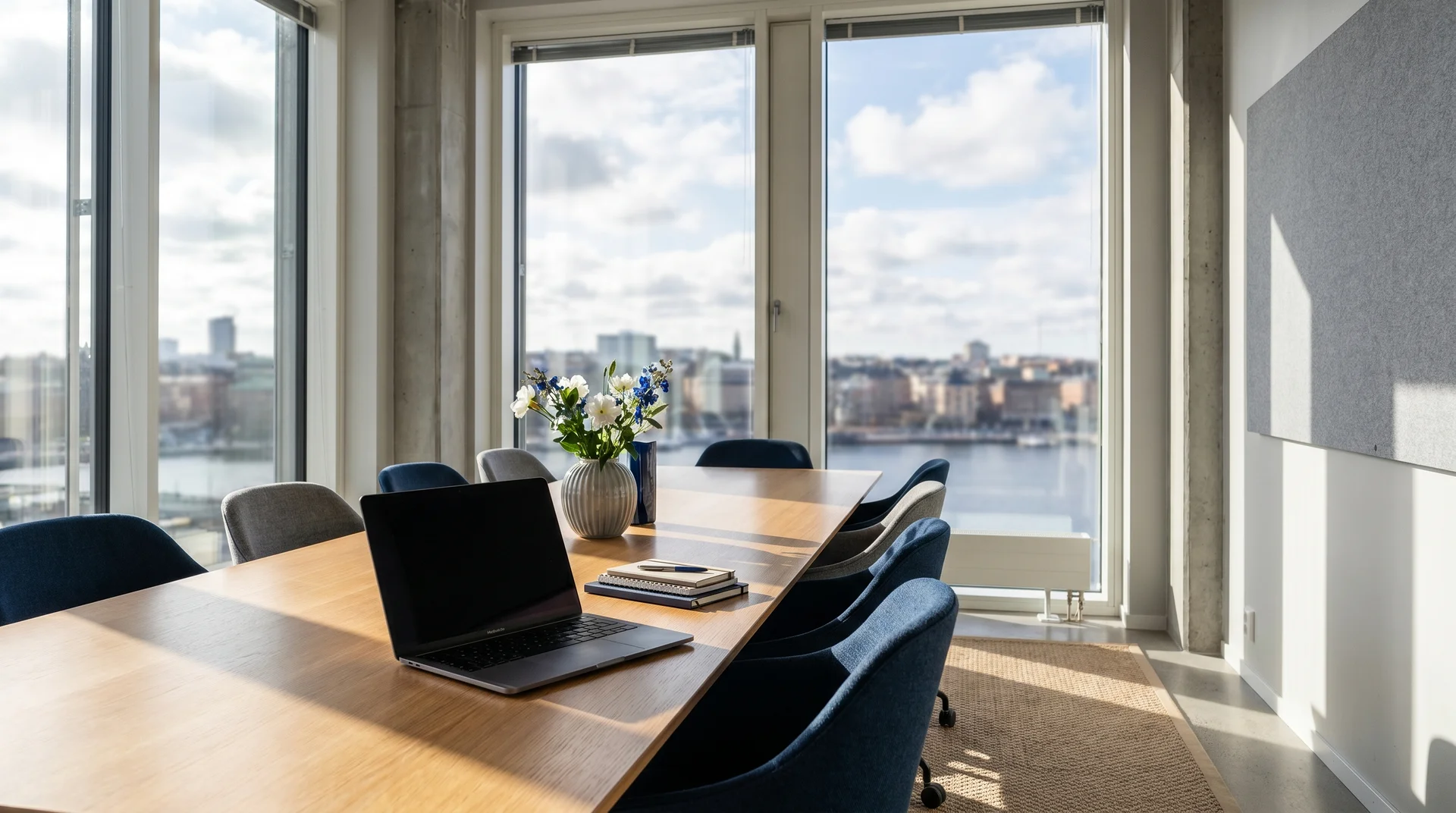 Modernt konferensrum med utsikt över vatten och stad genom stora fönster.